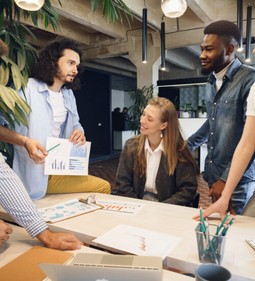 Team of diverse coworkers in modern office discuss their project together Team of diverse coworkers in modern office discuss their project together
